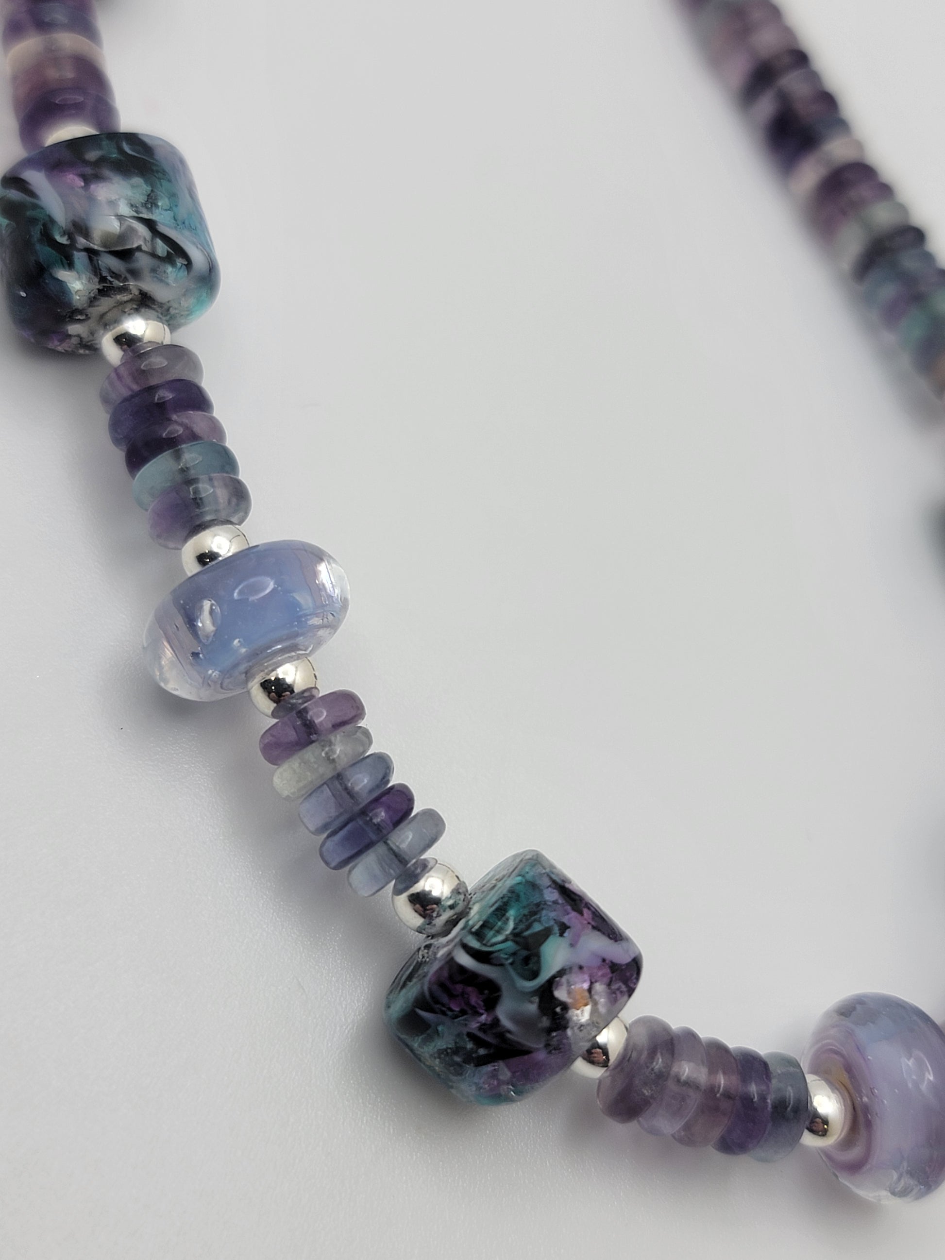 Close-up of a necklace with purple and blue beads on a white background
