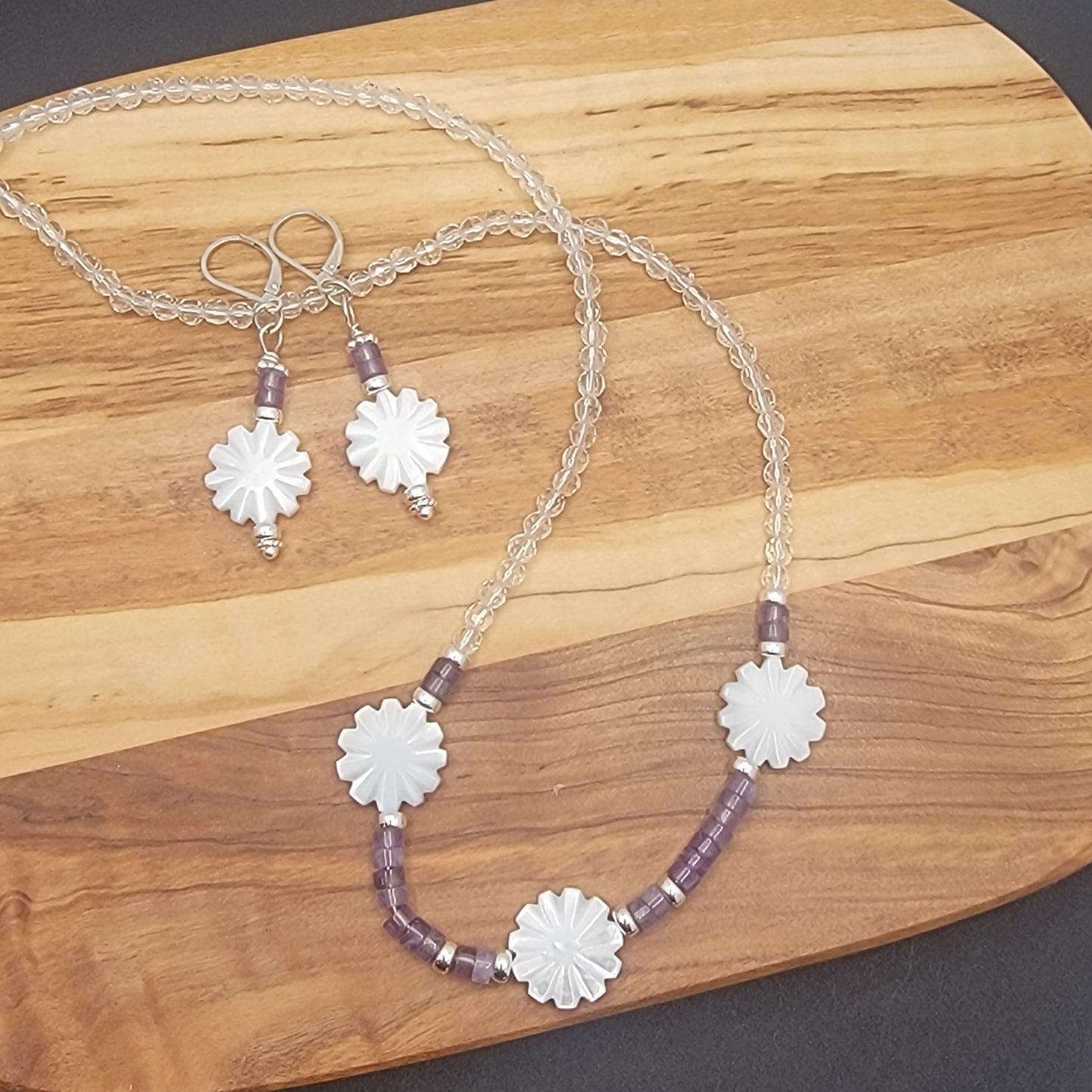 Necklace and earrings with floral designs on a wooden surface
