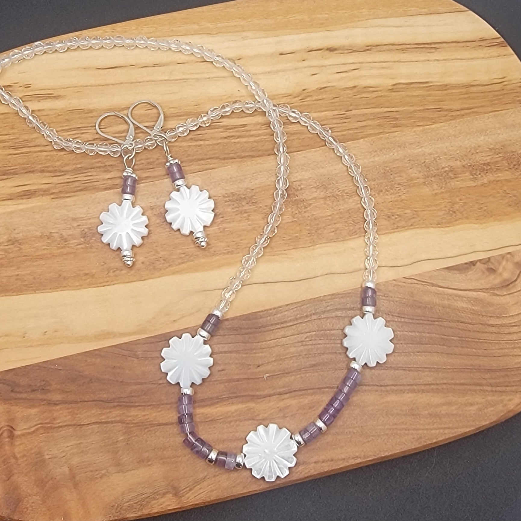 Necklace and earrings with floral designs on a wooden surface
