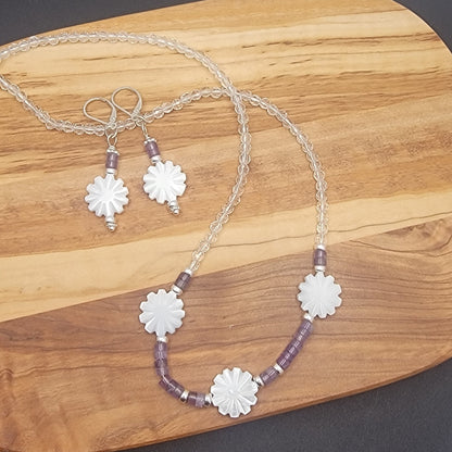 Necklace and earrings with floral designs on a wooden surface