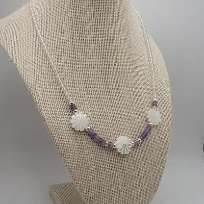 Necklace with purple and silver beads on a beige bust