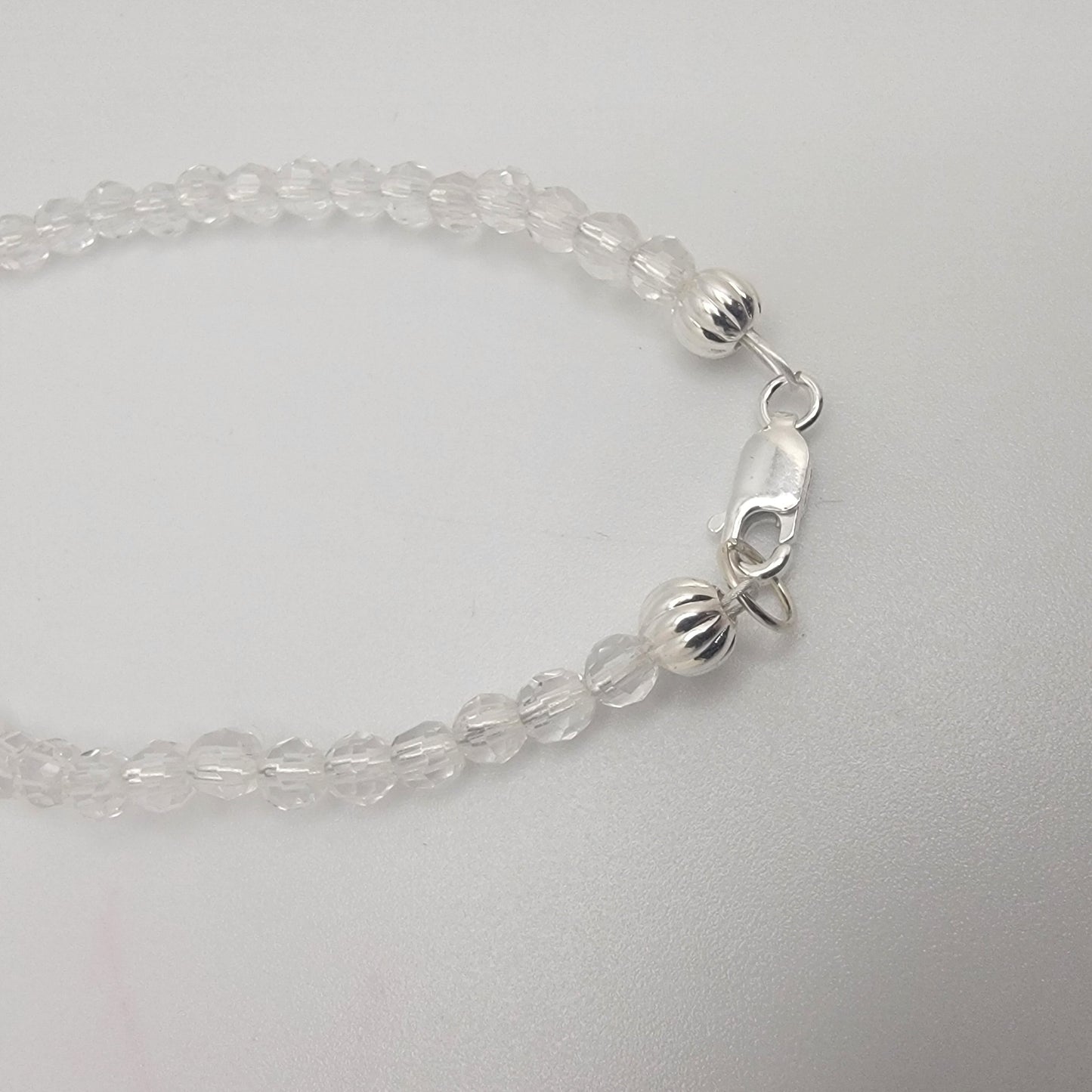 Clear beaded bracelet with silver clasp on a light gray background