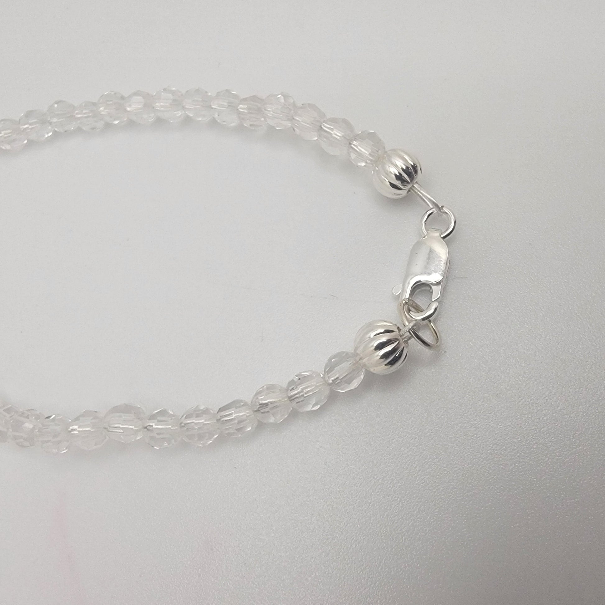 Clear beaded bracelet with silver clasp on a light gray background