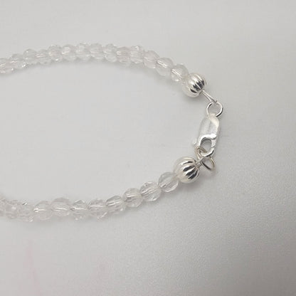 Clear beaded bracelet with silver clasp on a light gray background