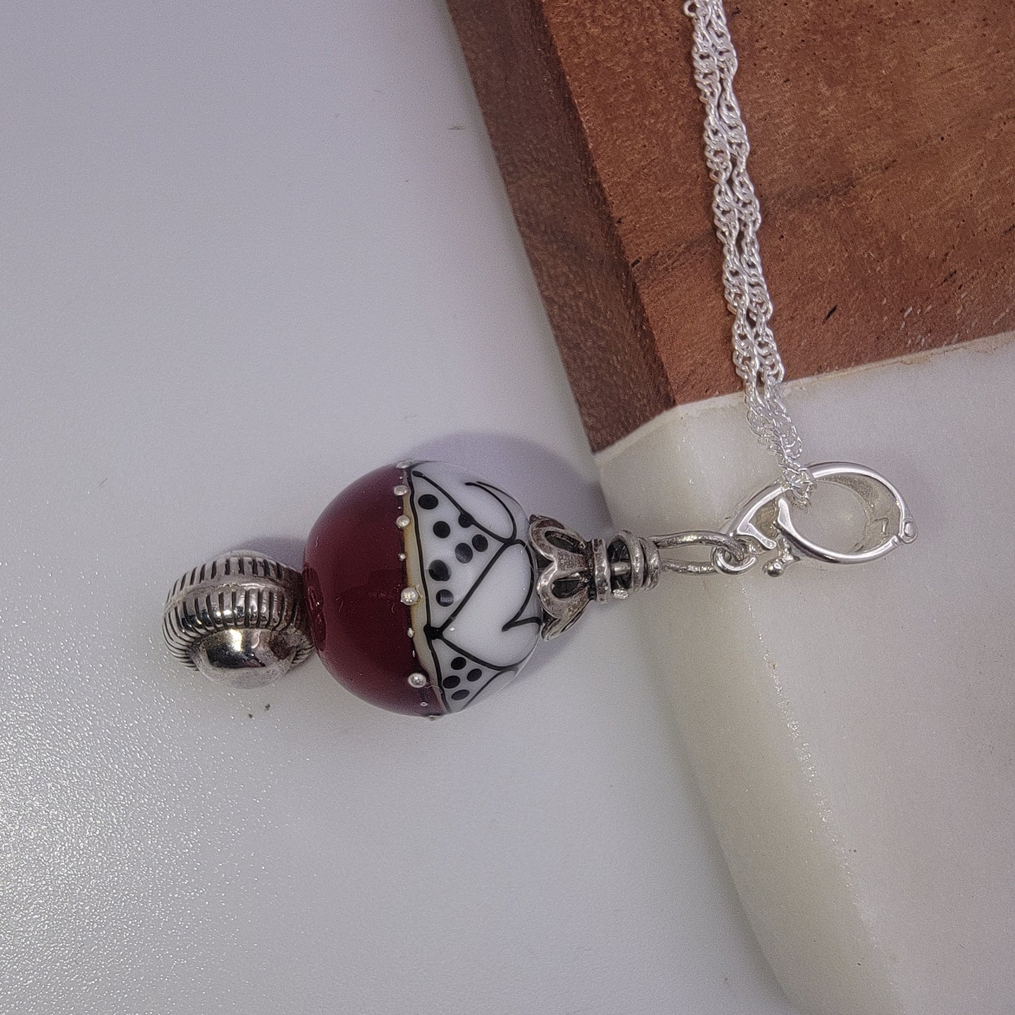 Necklace with a red and white bead charm on a white surface