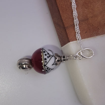 Necklace with a red and white bead charm on a white surface