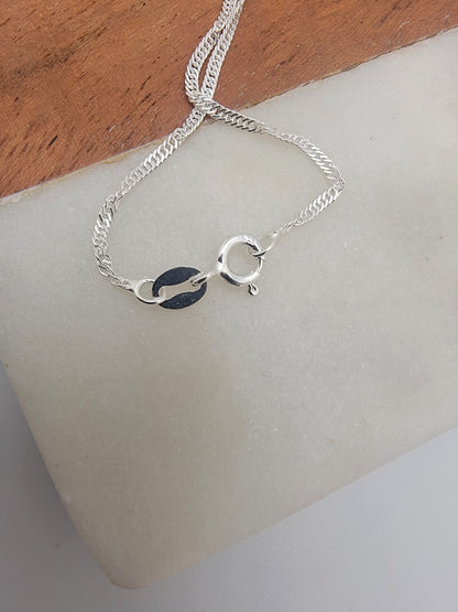 Silver necklace with clasp on a white surface