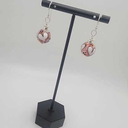 Pair of earrings on a black stand against a white background