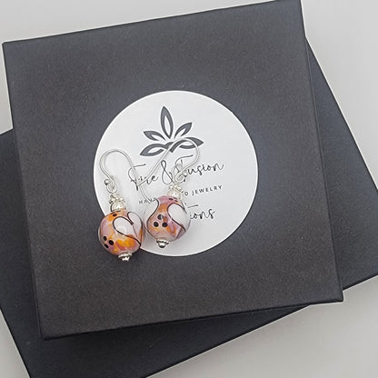 Pair of earrings on a black box with a brand label