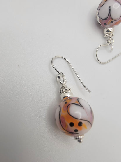 Pair of earrings with colorful beads on a light gray background