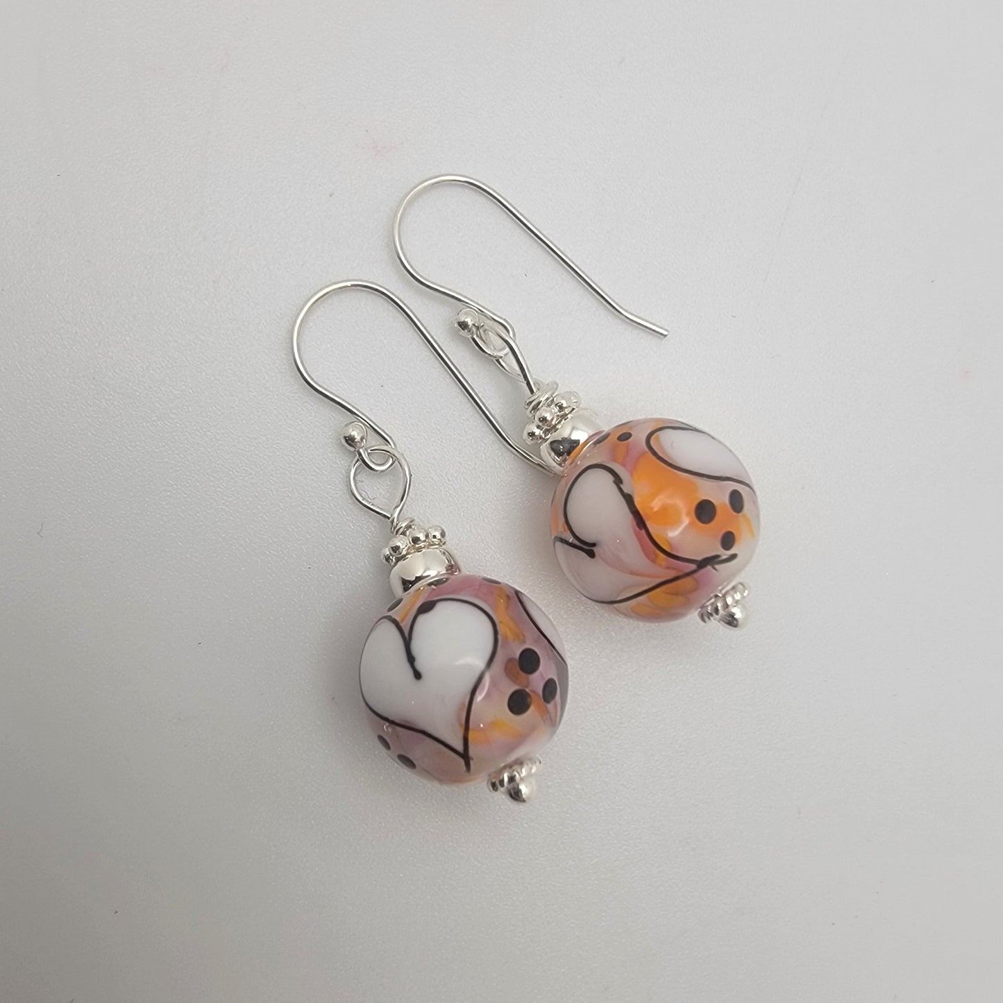 Pair of earrings with decorative beads on a light gray background