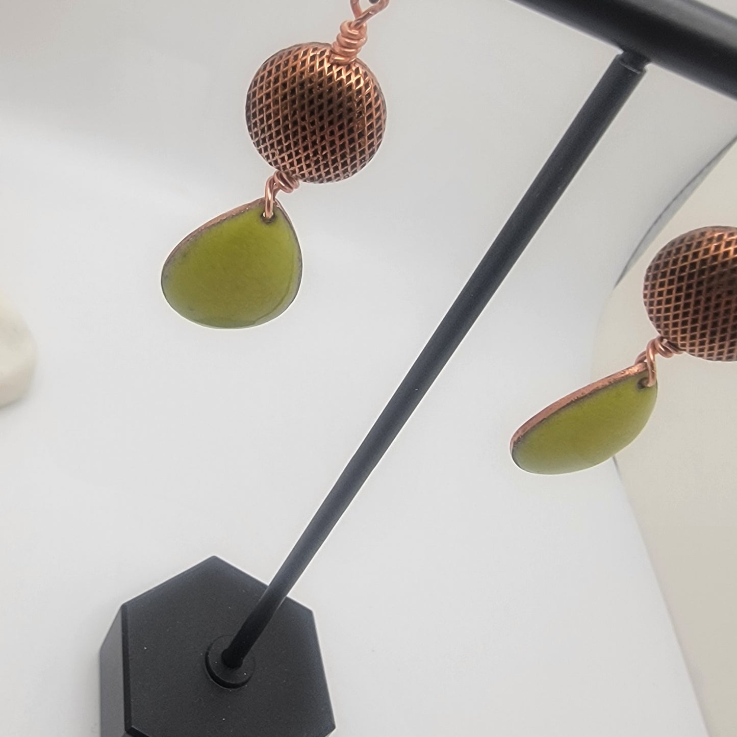 Earrings with green teardrop-shaped stones and copper accents on a white background