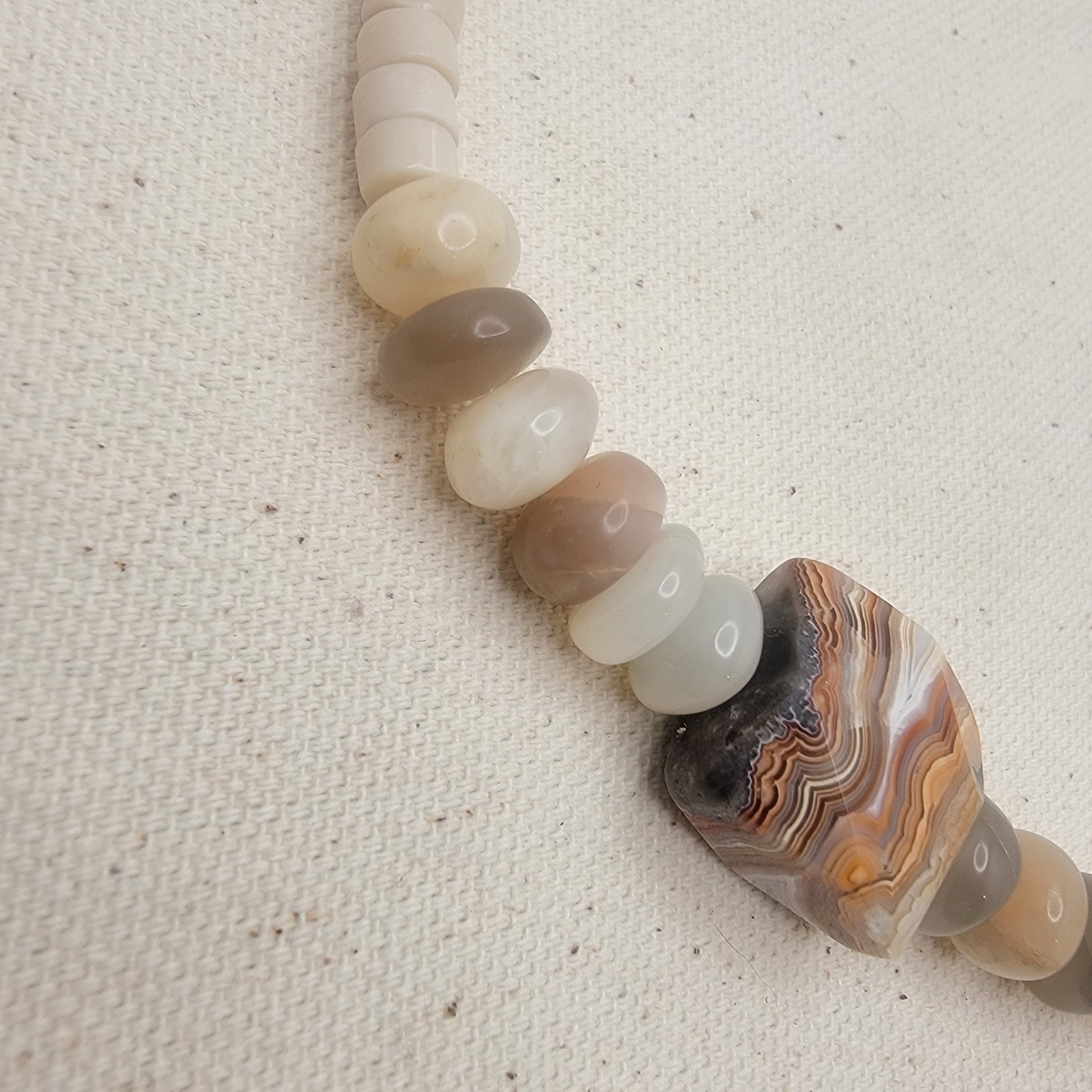 Necklace with agate and moonstones on a textured beige background