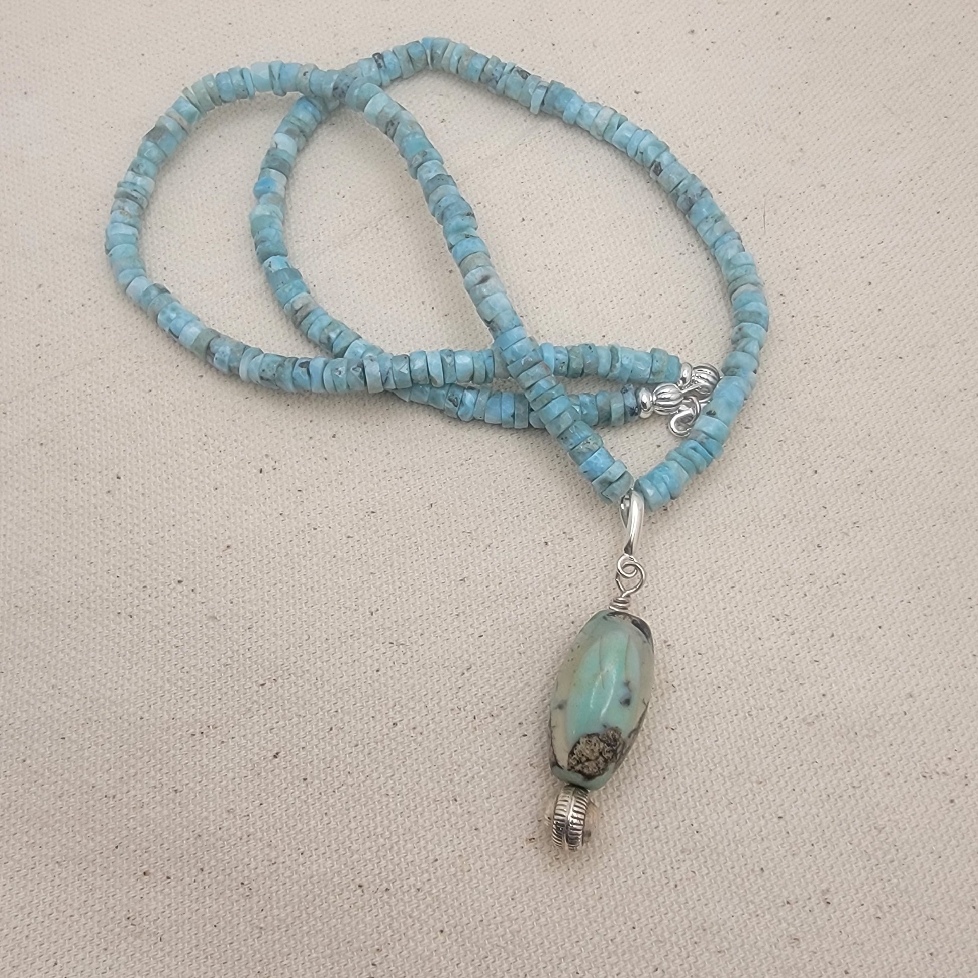 Larimar beaded necklace with an agate pendant on a beige background