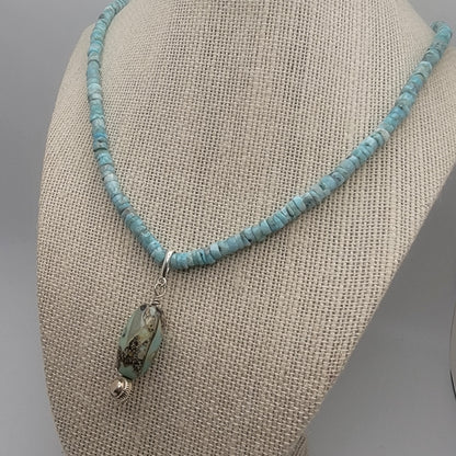 Larimar beaded necklace with an agate pendant on a beige fabric surface