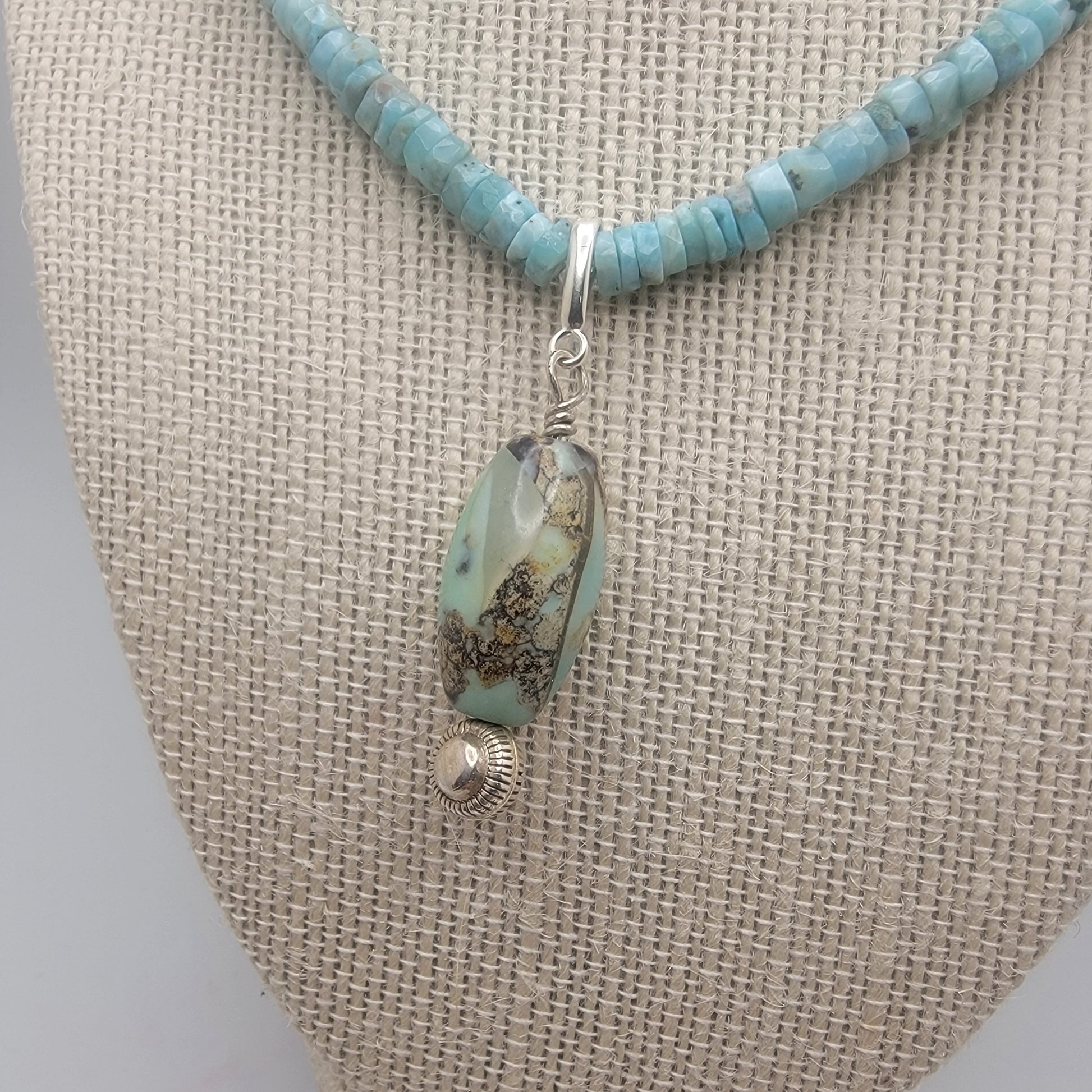 Larimar beaded necklace with a blue agate pendant on a gray surface