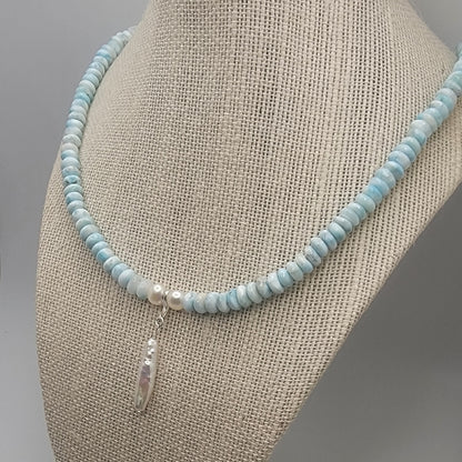 Beaded necklace with a pearl pendant on a mannequin bust against a neutral background