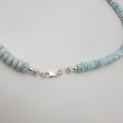 Necklace with light blue and white beaded chain on a light gray background
