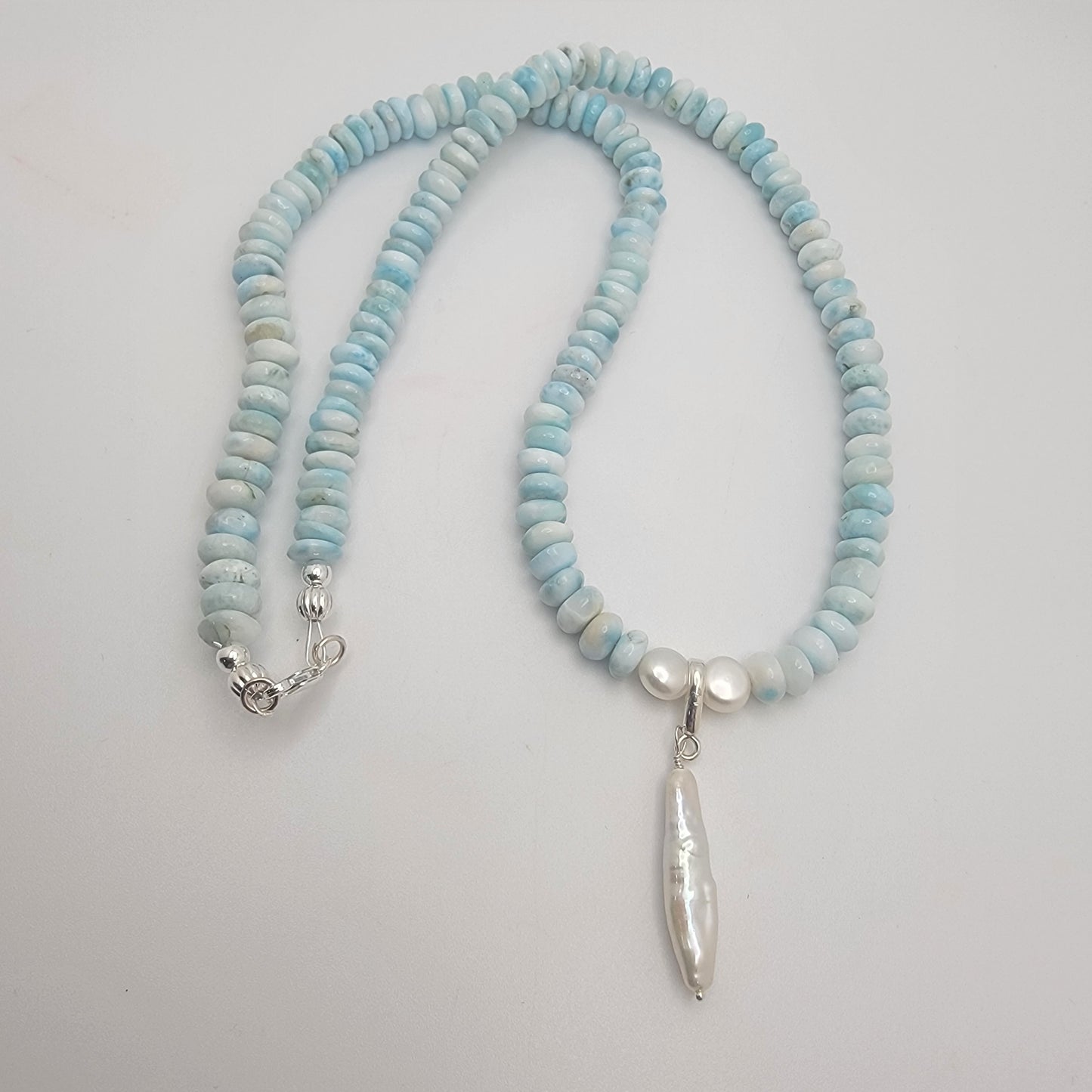 Necklace with light blue and white beads on a plain background