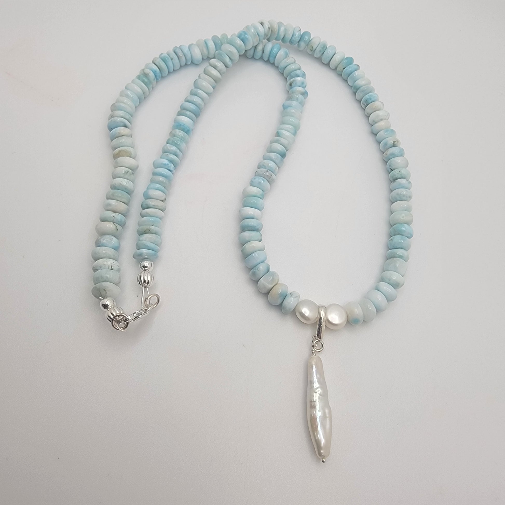 Necklace with light blue and white beads on a plain background