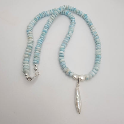 Necklace with light blue and white beads on a plain background