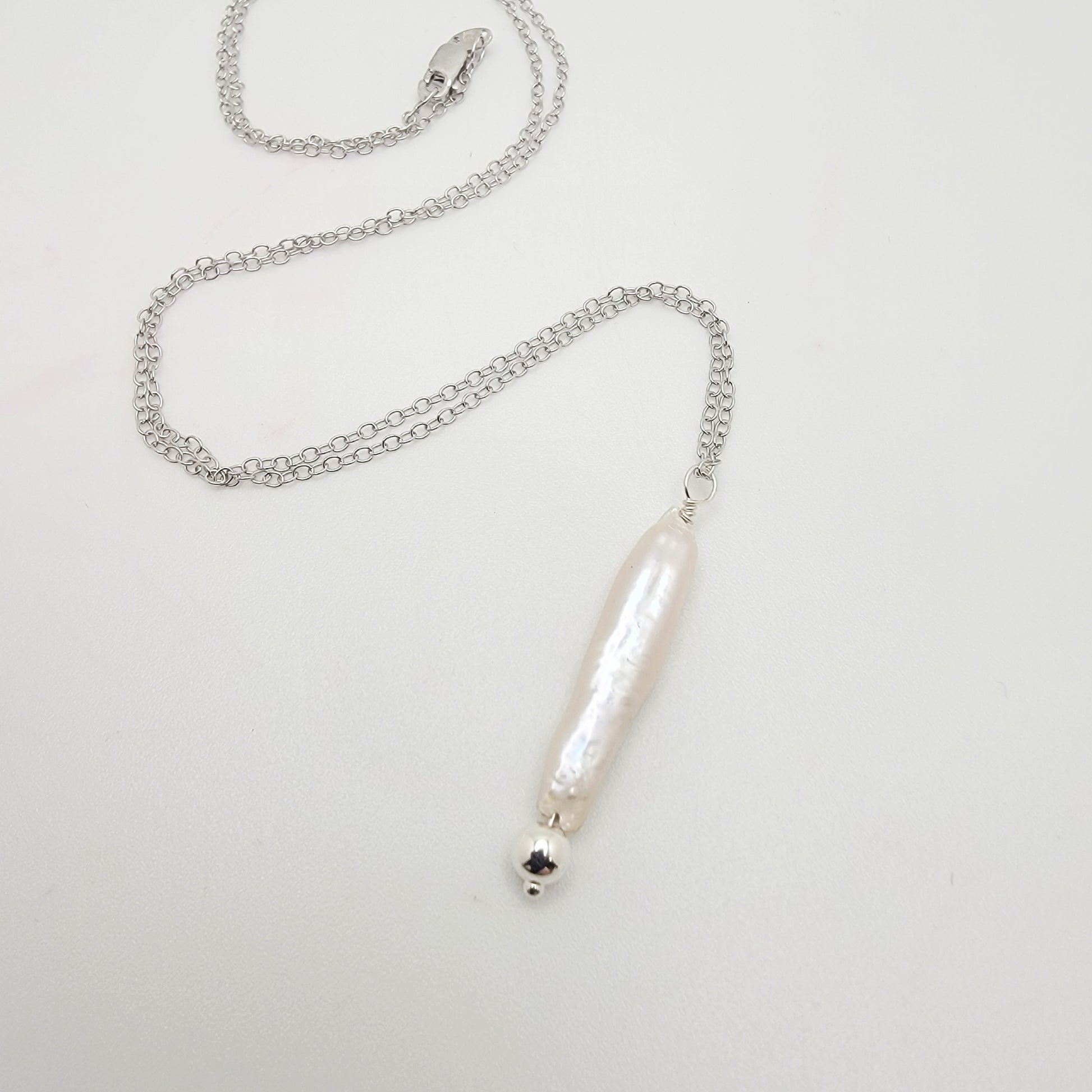 Silver necklace with a stick pearl pendant on a light gray background