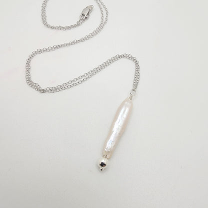 Silver necklace with a stick pearl pendant on a light gray background