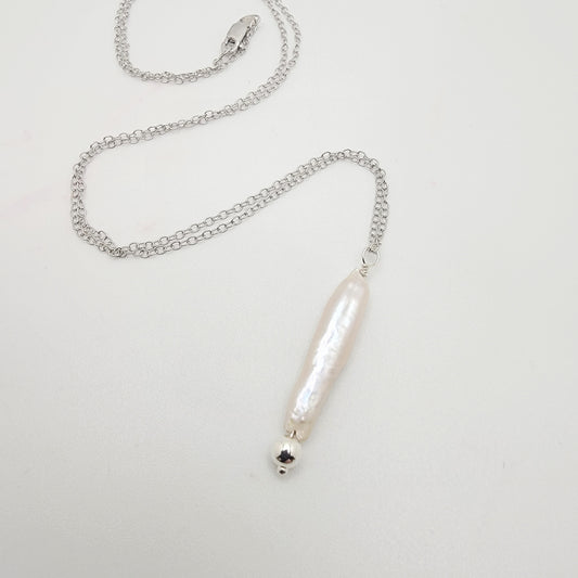 Silver necklace with a stick pearl pendant on a light gray background