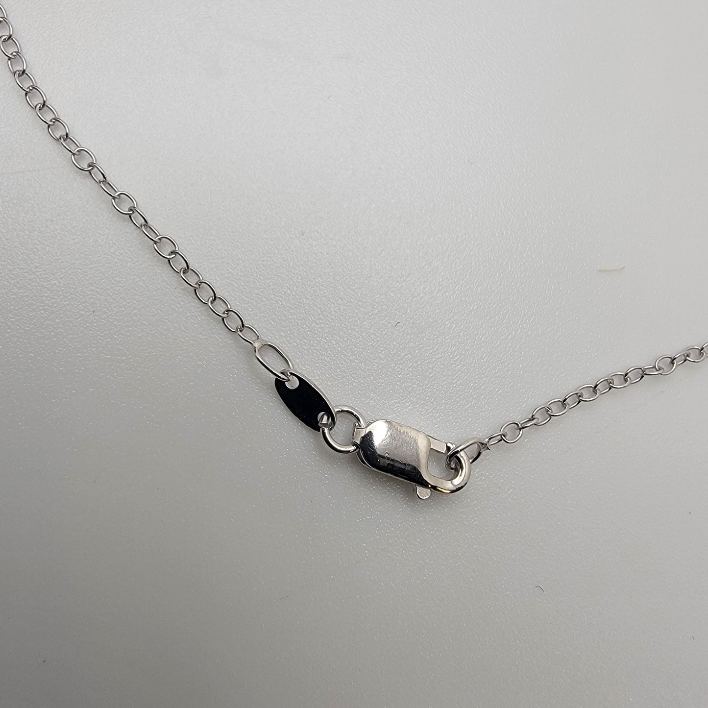 Silver necklace lobster clasp on a light gray background