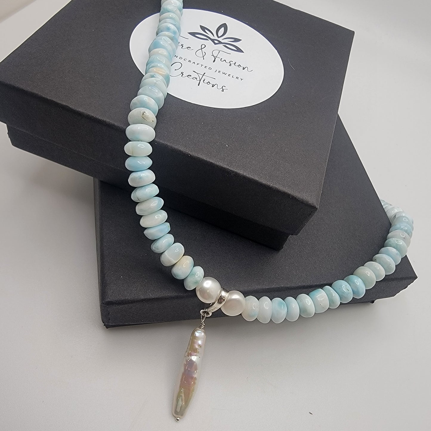 Blue and white beaded necklace with a pendant on a black branded jewelry box