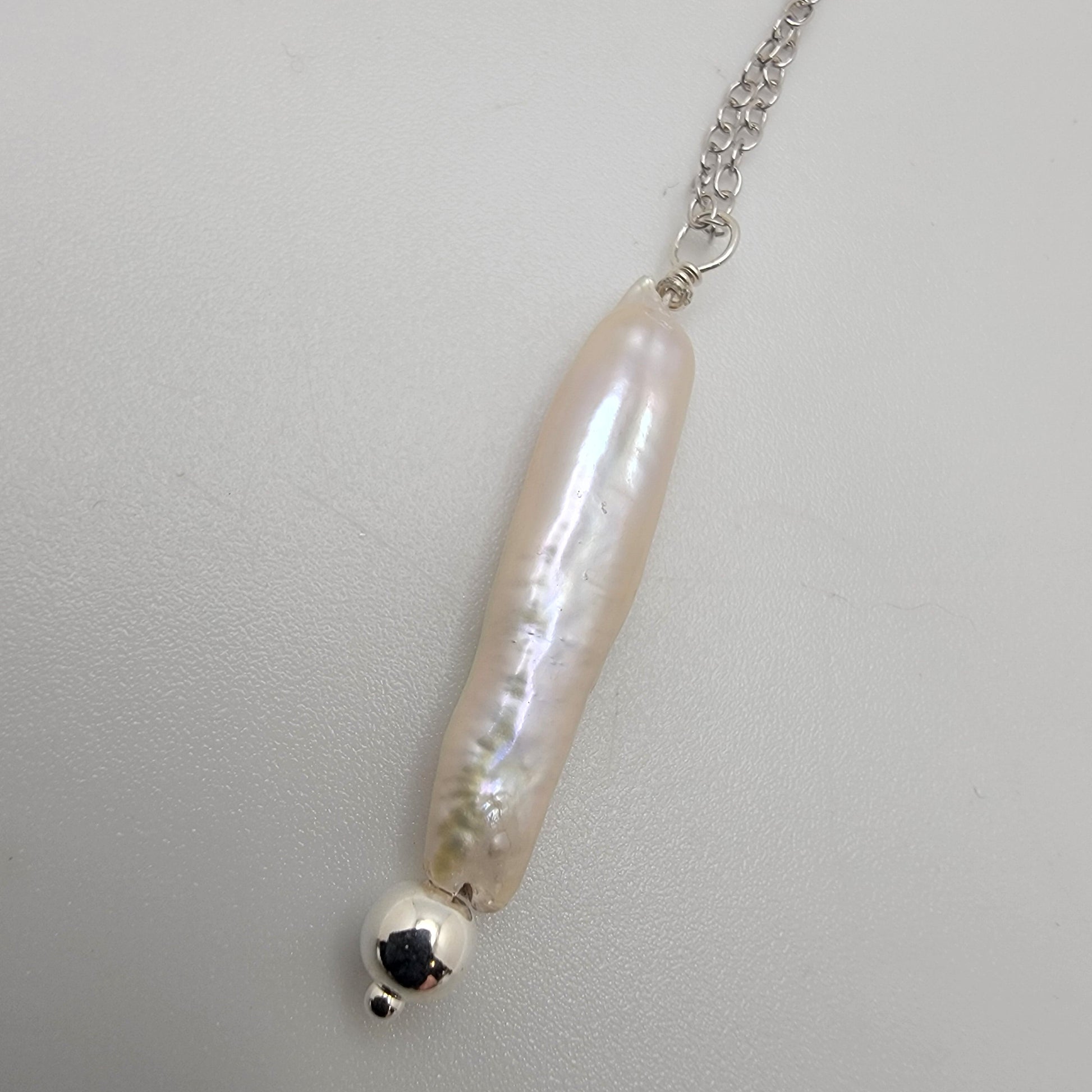 Pearl necklace with silver chain on a light gray background