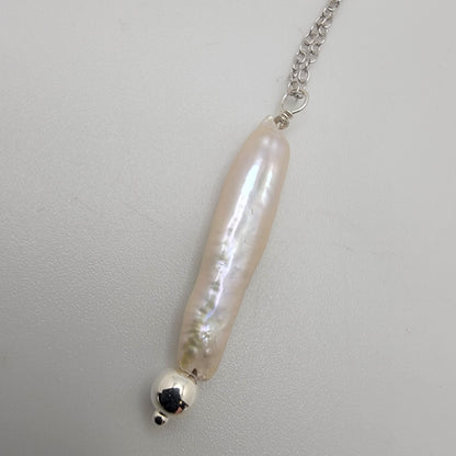 Pearl necklace with silver chain on a light gray background