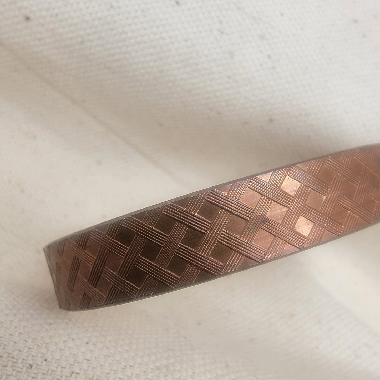 Copper textured bracelet on a white fabric background