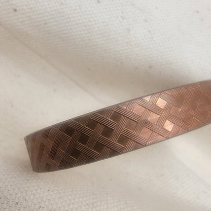 Copper textured bracelet on a white fabric background