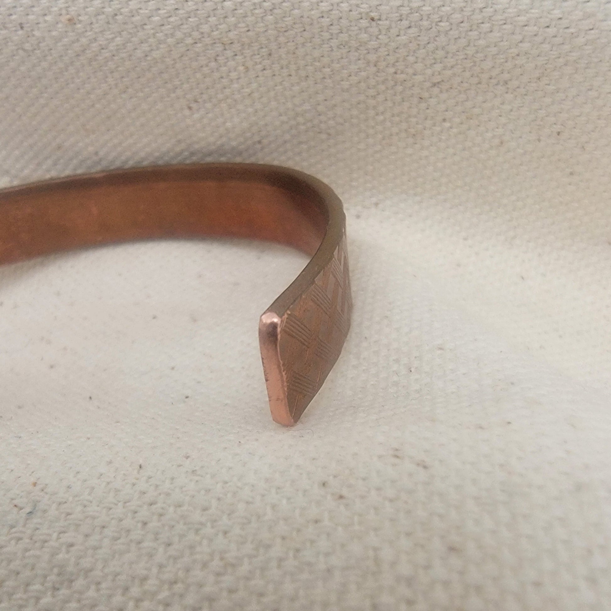 Copper bracelet on a textured beige background