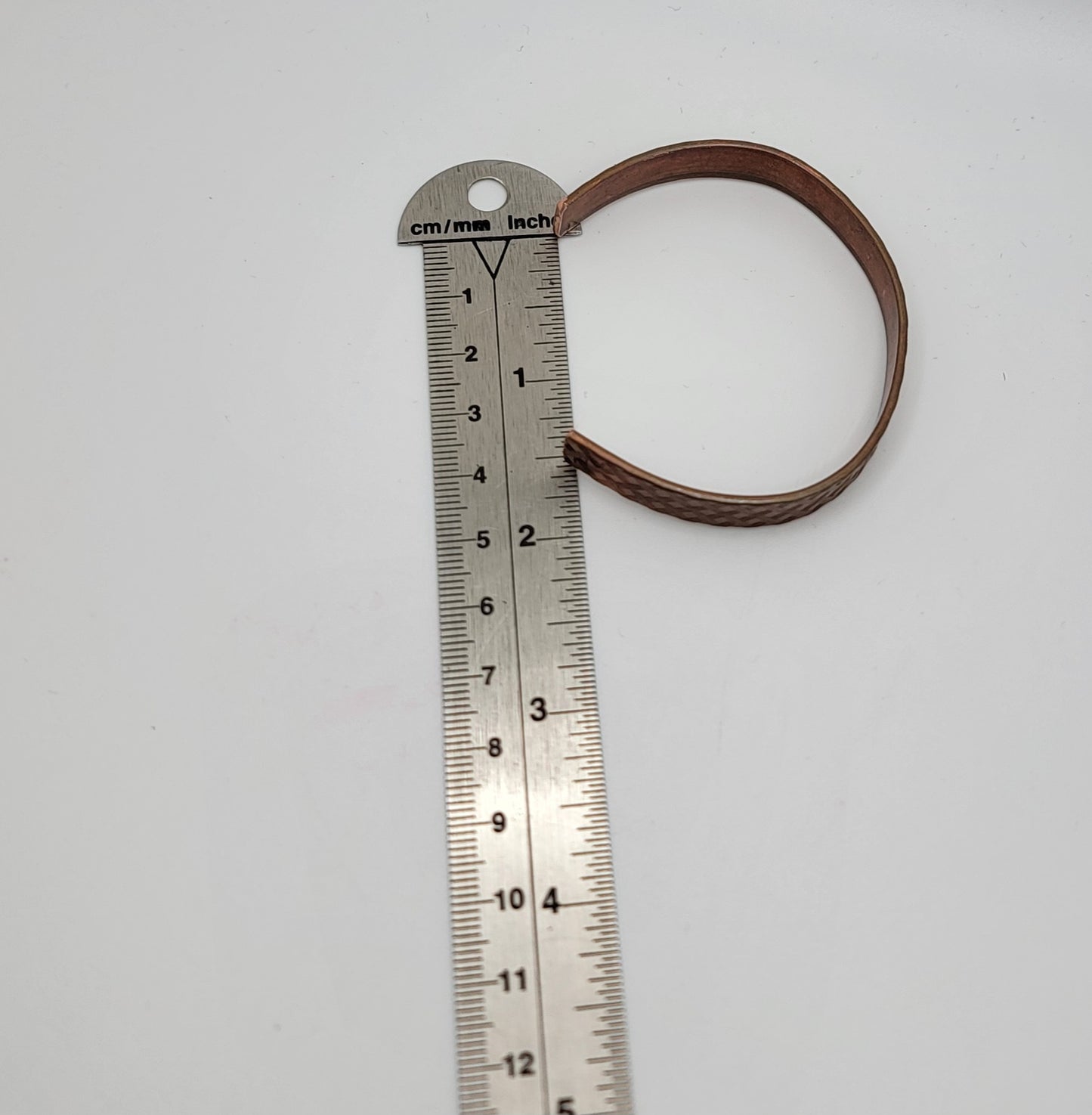 Metal ruler with a copper bracelet on a white background