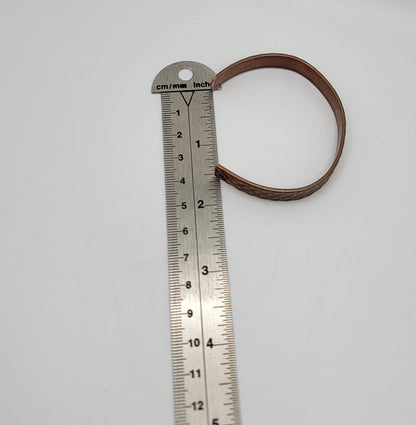 Metal ruler with a copper bracelet on a white background