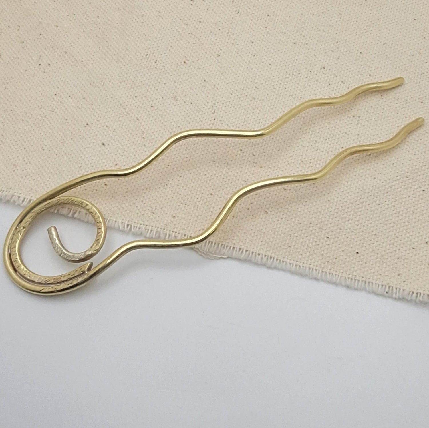 Brass hairpin on a beige fabric background