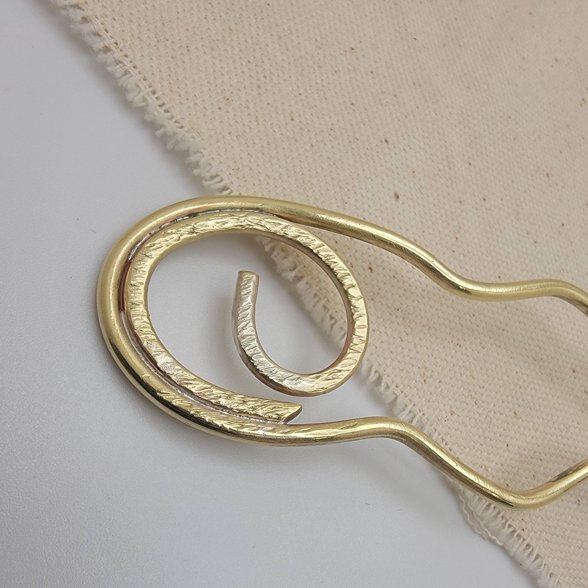 Brass hair pin on a beige fabric background