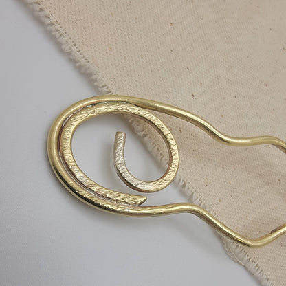Brass hair pin on a beige fabric background
