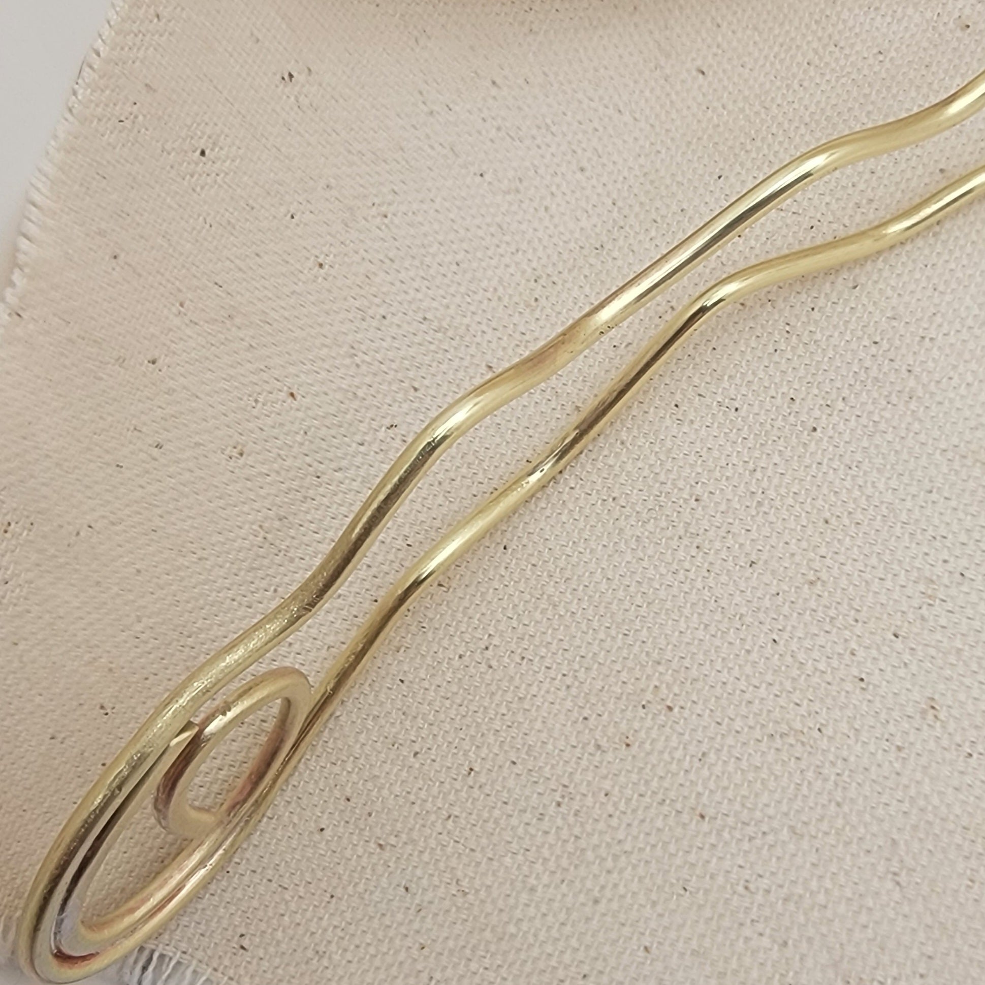 Brass hair pin on a beige fabric background