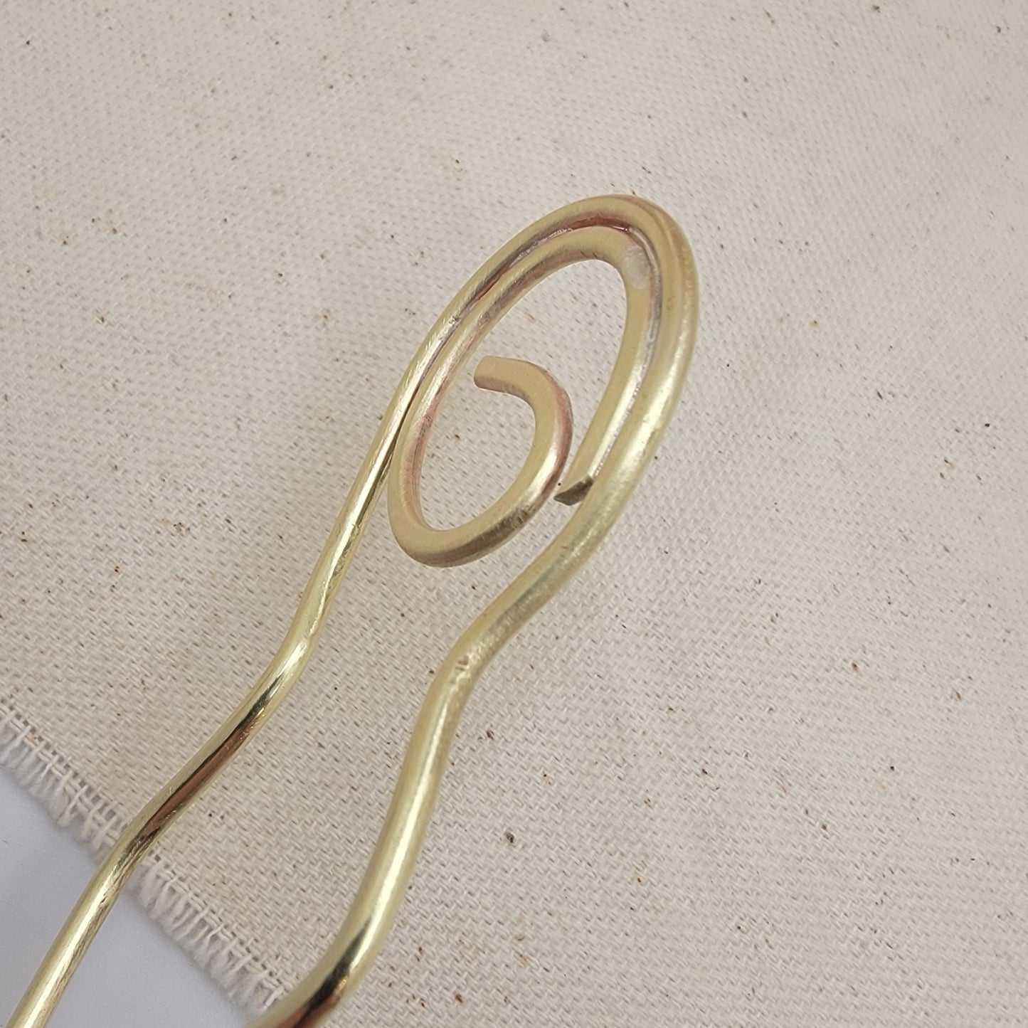 Brass hairpin on a textured beige background