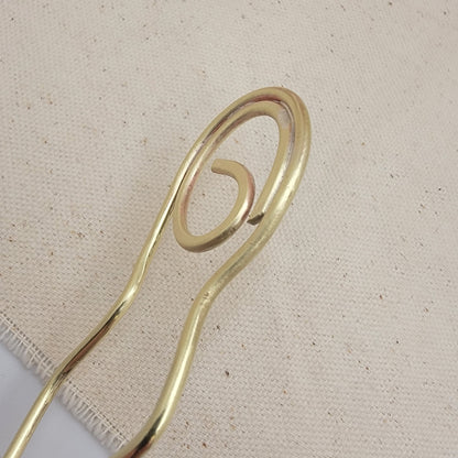 Brass hairpin on a textured beige background