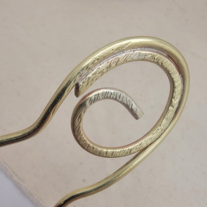 Brass spiral hair clip on a beige background