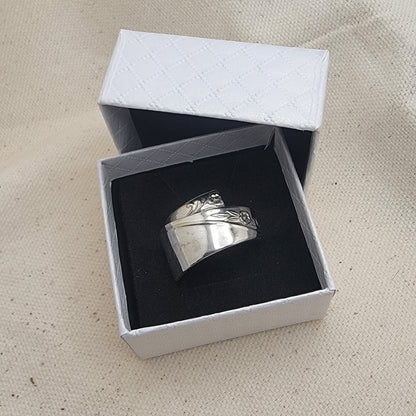 Silver ring in an open white box on a beige fabric background