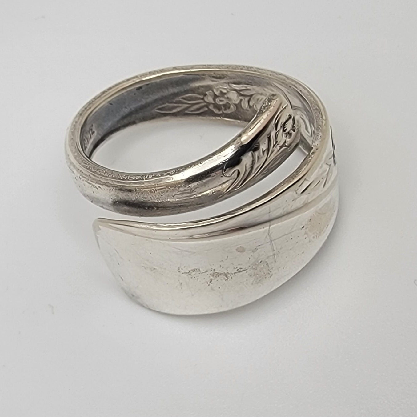 Silver ring with engraved floral design on a white background