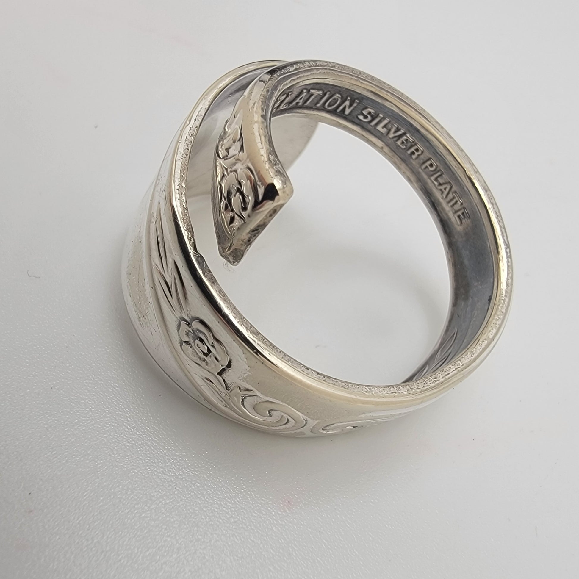Silver ring with intricate designs on a light gray background