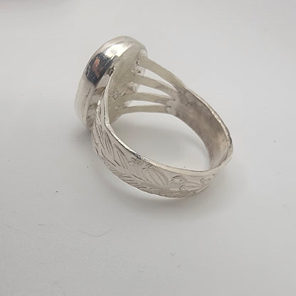 Silver ring with intricate design on a white background