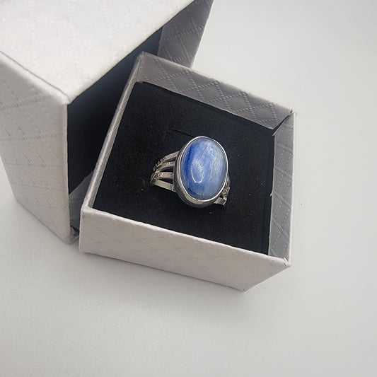 Silver ring with a blue stone in a white ring box with black insert on a white background