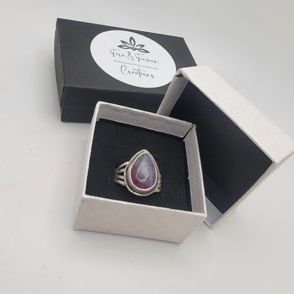 Silver ring with a purple stone in a jewelry box on a white background